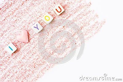 Phrase I Love You constructed from white letter cubes and pink heart shape sugar candy on red pencil strokes background on white Stock Photo