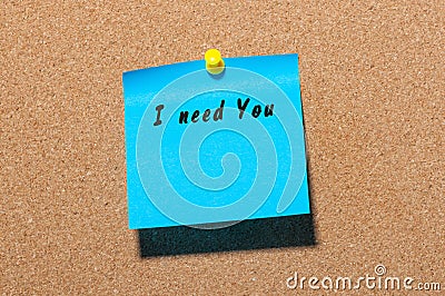 The phrase I need you written on blue sticker pinned to a cork notice board Stock Photo