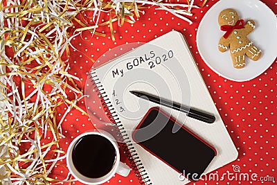 Phrase My Goals 2020 in a notebook, black pen and smart phone. Gingerbread and coffee on red background Stock Photo