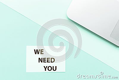 Phrase We need you and laptop on green background. Top view. Mockup, copy space. Recruitment announcement, job search Stock Photo