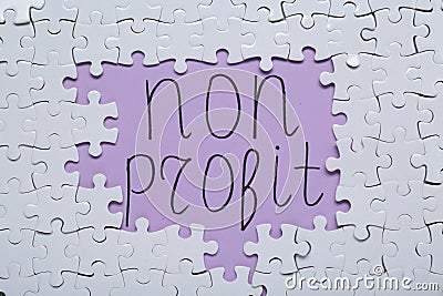 Phrase Non Profit surrounded by many white puzzles on purple background, flat lay Stock Photo