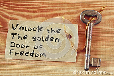 The phrase - unlock the golden door of freedom written on note attached to key Stock Photo