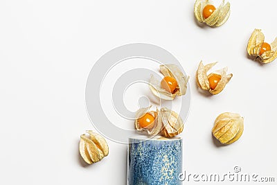 Physalis fruit or Physalis peruviana, small golden berries scattered from ceramic cup Stock Photo