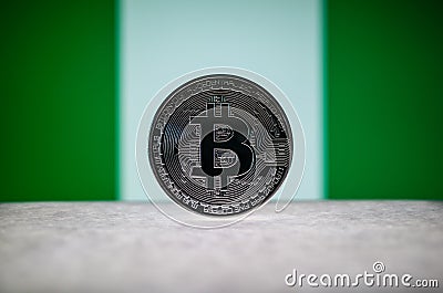 Physical silver version of Bitcoin BTC and Nigeria Flag on the background. Conceptual image for investors in Stock Photo