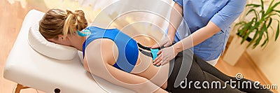 Physical therapist applying kinesio tape on female patient`s lower back. Kinesiology, physical therapy, rehabilitation. Stock Photo