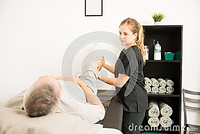 Physical Therapist Helping Patient With Leg Exercise For Pain Re Stock Photo