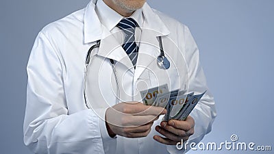 Physician counting bundle of money, expensive medicine at private clinic, bribe Stock Photo