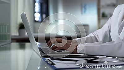 Physician typing on laptop, patients medical record, healthcare technology Stock Photo