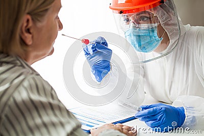 Medical worker in personal protective equipment wearing face shield performing PCR COVID-19 nasal swab test Stock Photo
