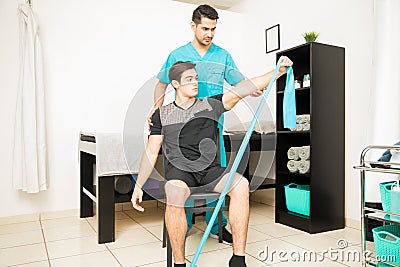 Physiotherapist Assisting Athlete In Performing Stretching Exercise With Resistance Band Stock Photo