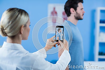 Physiotherapist clicking photo of a male patient Stock Photo