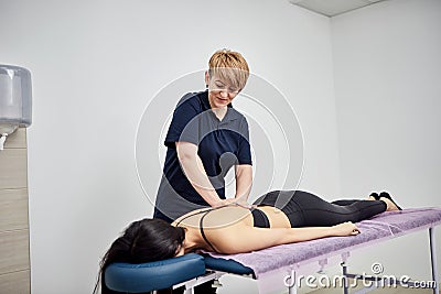 Physiotherapist massaging a female patient sportswoman with damaged muscles in kinesio clinic. Treatment of sports injuries Stock Photo