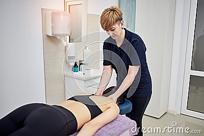Physiotherapist massaging a female patient sportswoman with damaged muscles in kinesio clinic. Treatment of sports injuries Stock Photo