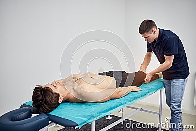 Physiotherapist massaging a male patient sportsman with damaged muscles in kinesio clinic. Treatment of sports injuries Stock Photo