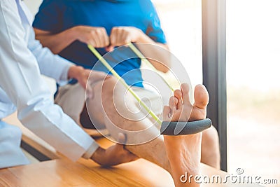 Physiotherapist man giving resistance band exercise treatment About knee of athlete male patient Physical therapy concept Stock Photo