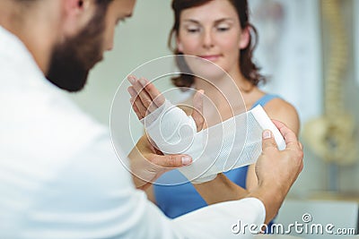 Physiotherapist putting bandage on injured hand of patient Stock Photo