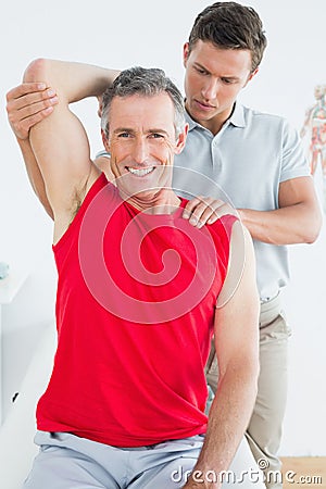 Physiotherapist stretching a smiling mature mans arm Stock Photo