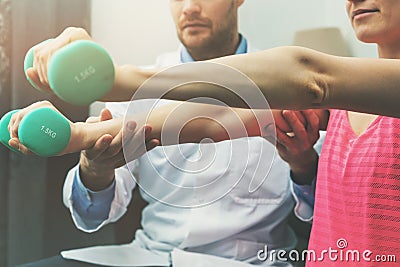 Physiotherapy - physiotherapist help woman patient to recover from hand injury. dumbbell exercises Stock Photo