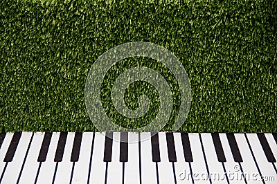 Piano keys against a green grassy wall Stock Photo