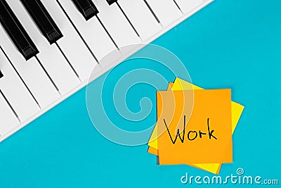 Piano and paper reminder with word Work on blue background. Stock Photo