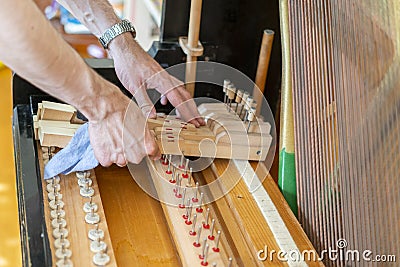 Piano tuning process. closeup of hand and tools of tuner working on grand piano. Detailed view of Upright Piano during a tuning. Stock Photo