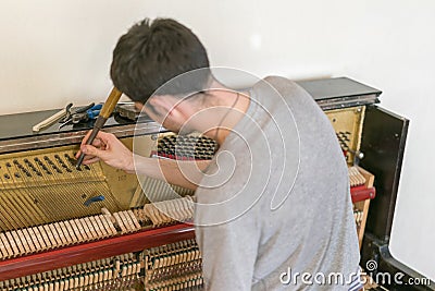 Piano tuning process. closeup of hand and tools of tuner working on grand piano. Detailed view of Upright Piano during a tuning Stock Photo