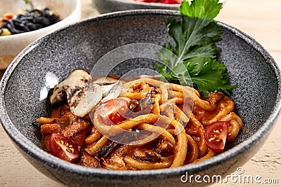 Pichi with mushrooms and creamy tomato allione in gray bowl Stock Photo