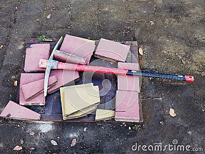 Pickaxe lies on the ground with pieces of paving slabs. Repair of sidewalks. Laying street tiles Stock Photo