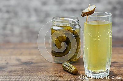 Pickle juice in glass and a can of pickled cucumbers on wooden table Stock Photo
