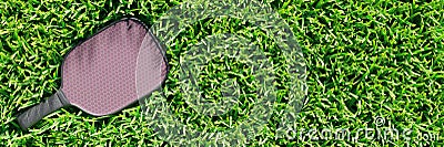 Pickleball racket on the lawn grass of a sports field. Stock Photo