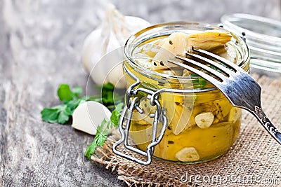 Pickled artichoke with garlic in a glass jar on rustic wooden t Stock Photo