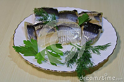 Pickled chopped herring with herbs on a white plate on the table. Stock Photo