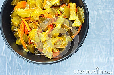 Pickled fermented cucumbers and carrots in a dark salad bowl. Top View Stock Photo