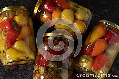 Pickled (fermented) vegetables in glass jars on dark background, top view Stock Photo