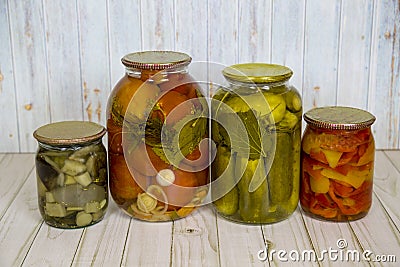 Pickles tomatoes squash peppers rolled in glass jars on a wooden table light brown. Vegetables, products Stock Photo