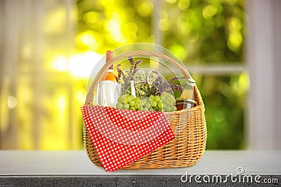 Picnic basket with flowers, wine and food on stone table indoors Stock Photo