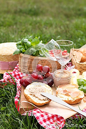 Picnic blanket with wineglasses and food on green grass Stock Photo
