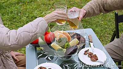 During a picnic in the country, a man and a woman clink glasses with beer, celebrate the holiday Stock Photo