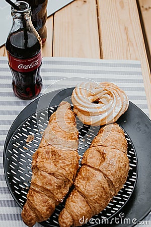 Picnic with croissants and Coca Cola on a wooden table at the camping Editorial Stock Photo