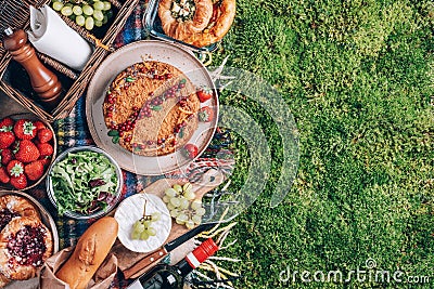 Picnic straw basket with healthy food, accessories. Summer picnic with cake, fruits, cheese, wine and snacks on plaid Stock Photo