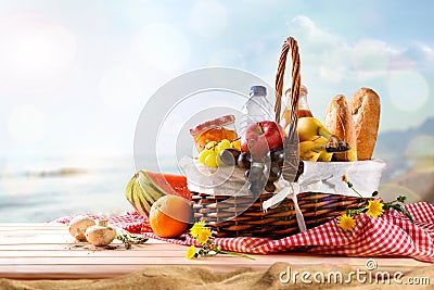 Picnic wicker basket with food on table on the beach Stock Photo