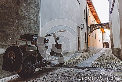 Old grey scooter parked in a narrow alley in Ascona Stock Photo