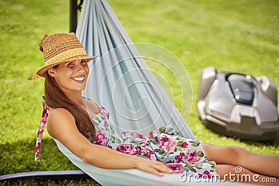 Pretty woman Relaxing In Hammock with automower in background Stock Photo