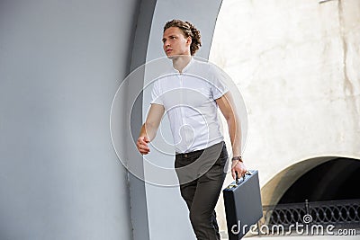 Picture of Calm curly business man with briefcase looking away Stock Photo