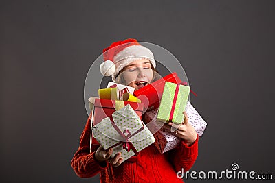 Picture of cheerful santa helper girl with many gifts box isolated on gray background Stock Photo