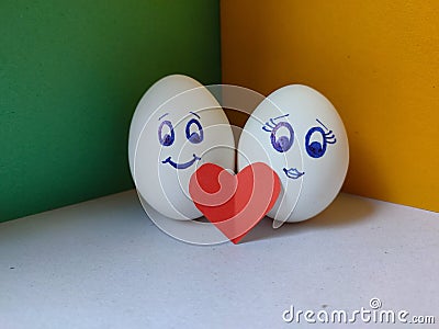 Picture of couple faces drawn on eggs with red heart and yellow and green background. Stock Photo