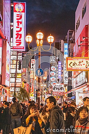 A picture of Dotonbori at night, filled with people and signs advertising shops. Editorial Stock Photo