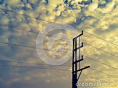 Electrical poles of high voltage transmission lines of 440 volt running on porcelain insulation with cloudy sky background Stock Photo