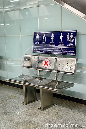 Picture of empty waiting chairs with social distancing sign, red cross mark. Metallic chair with social distancing symbol on seat Editorial Stock Photo