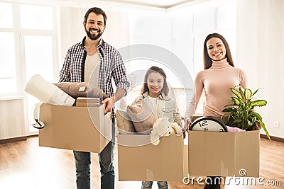 A picture of family where everybody is holding a box of different stuff in their hands. They are standing in an empty Stock Photo